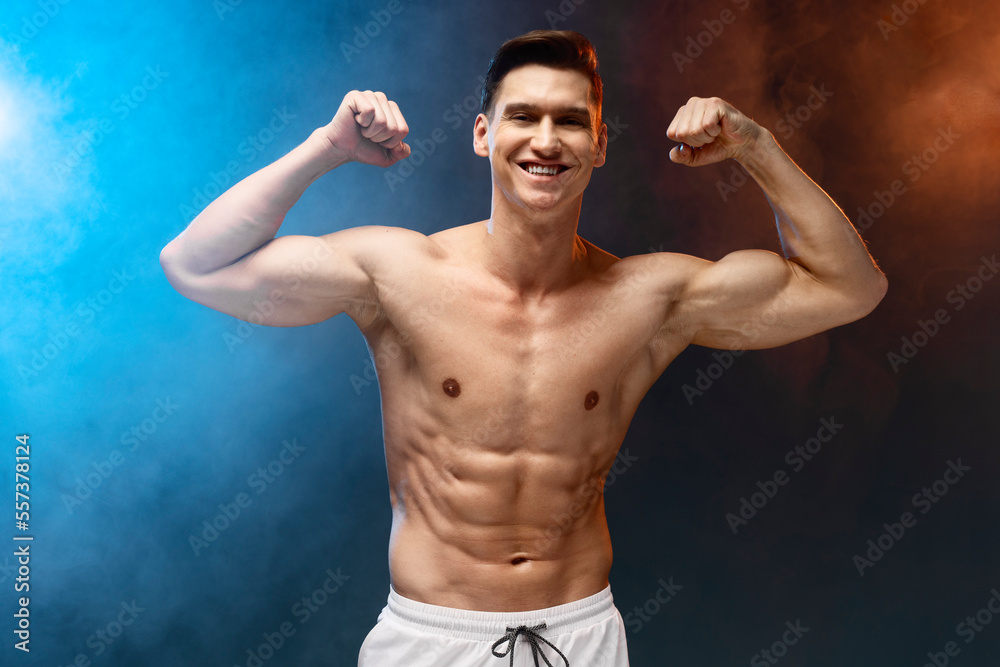 Young athletic man with naked torso isolated on black background with neon fume