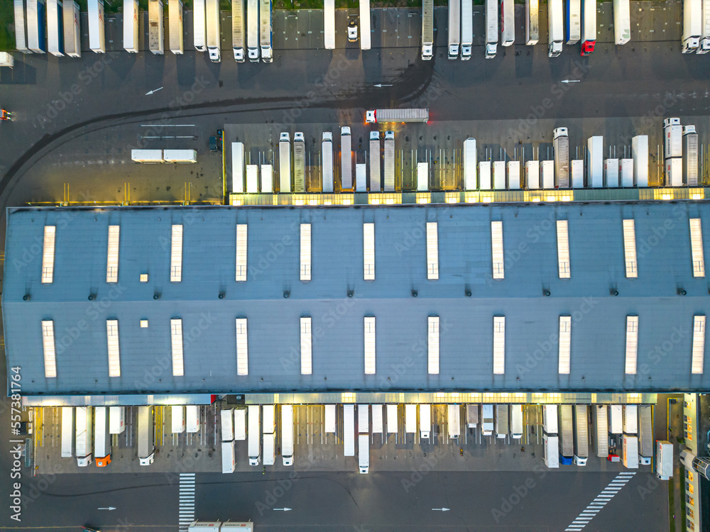 Aerial view of goods warehouse Night. Logistics center in industrial city zone from above. Aerial view of trucks loading at logistic center Aerial view of goods warehouse Night. Logistics center in industrial city zone from above. Aerial view of trucks loading at logistic center