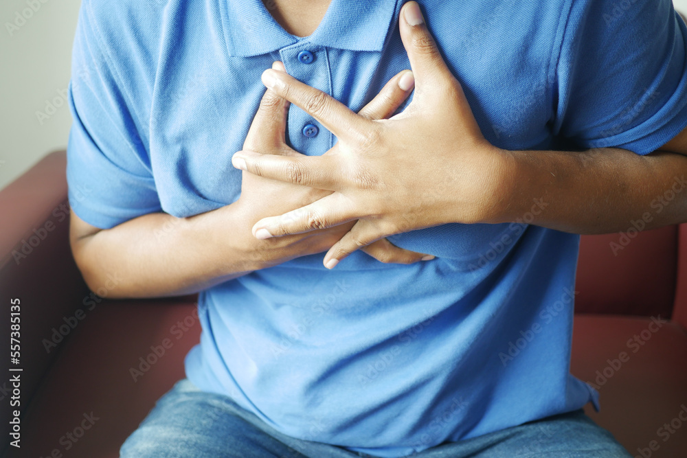 young man suffering pain in heart and holding chest with hand 