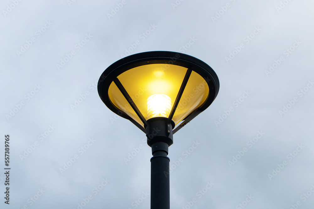 Light bulb night lamp lighting for safety. vintage street lamp post lantern lanterns at the park or enable to be turned on at the party. with sky and clouds in background during nighttime.