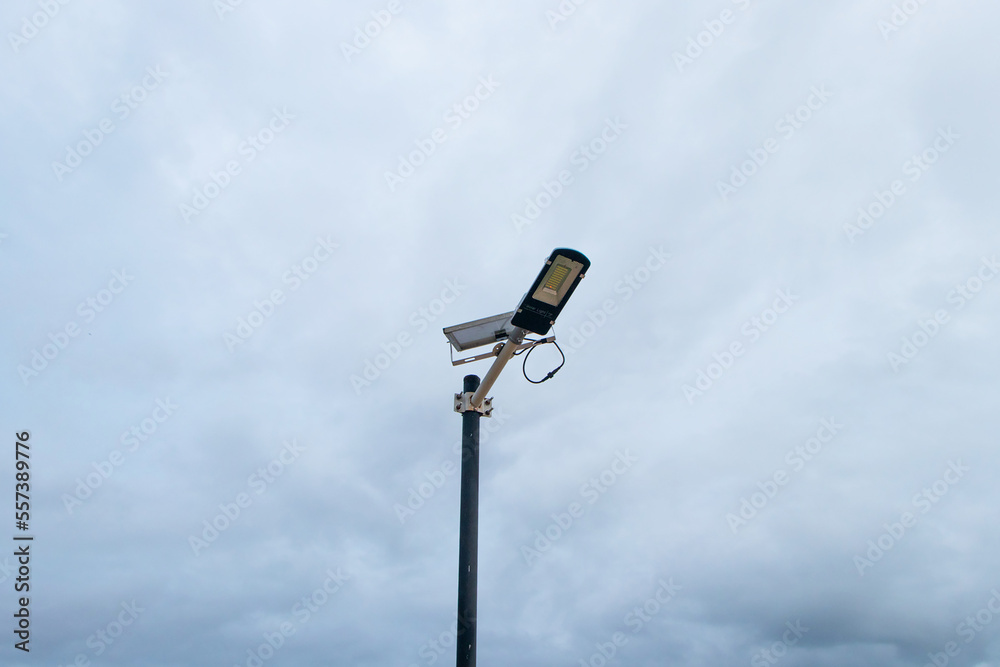 Solar panel small powered street light bulbs side walking street in park. Concept of saving electricity by using solar energy as renewable energy. with sky and clouds in background during nighttime. Solar panel small powered street light bulbs side walking street in park. Concept of saving electricity by using solar energy as renewable energy. with sky and clouds in background during nighttime.