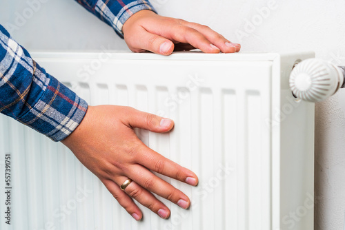 Hands on the radiator of the heating system, selective focus. Background