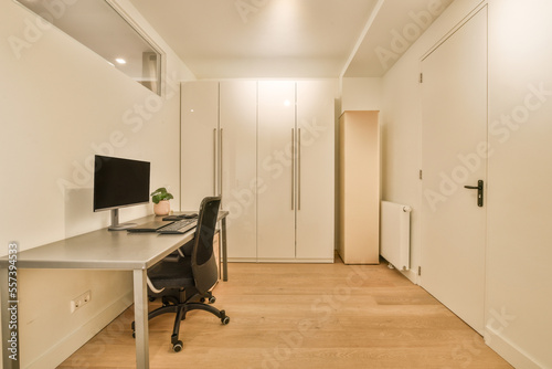 an empty room with a computer on the desk and two white closets in the wall to the left side photo
