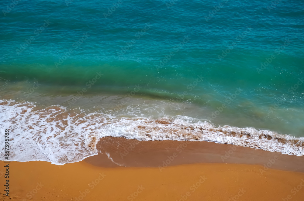 Obraz premium Aerial view of surf in turquoise sea meets red sandy beach