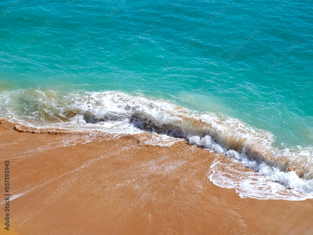 Aerial view of surf in turquoise sea meets red sandy beach