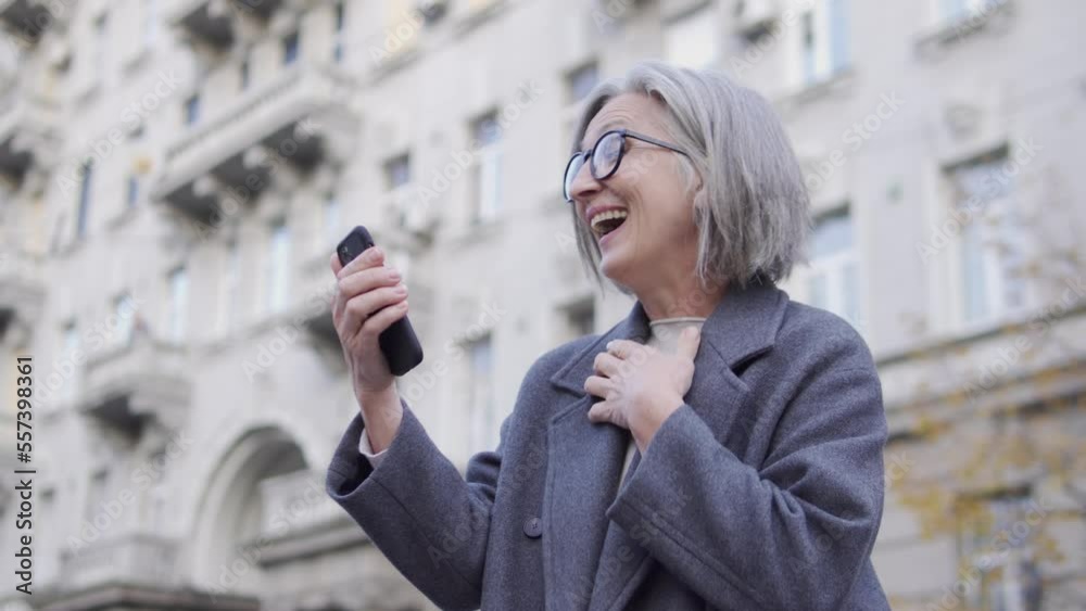 Mature lady checking balance on smartphone and rejoicing, received a pay raise Mature lady checking balance on smartphone and rejoicing, received a pay raise