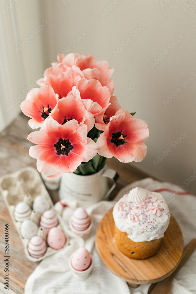 Easter cake Panettone and colored eggs flat lay food photo. Easter traditions and decorations. Pink tulips in a vase top view