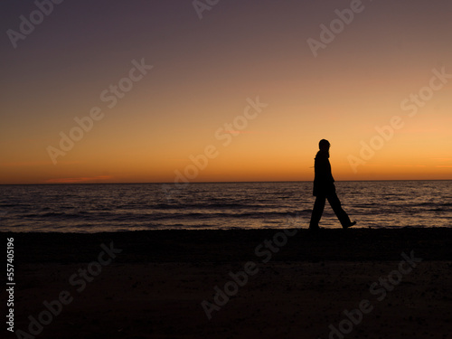 silhouette of person walking on the beach at sunset
