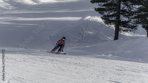 A young experienced skier, quickly descends a snow-covered slope, in winter on a piste at a ski resort. Southern Alps, France.