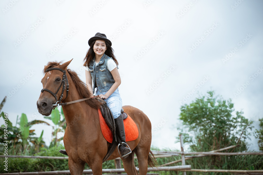 beautiful cowboy girl riding a horse while going with her back to the camera on an outdoor background