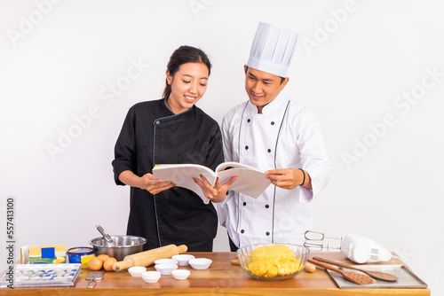 male and female chefs using cookbooks standing near table on isolated background