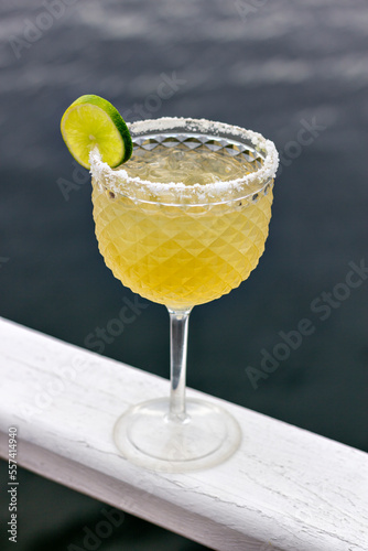 Tequila and beer cocktail (cozumel), garnished with salt and a slice of lemon, resting on a white board, with the sea in the background
