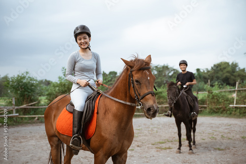 female athlete riding horse to train with male athlete on outdoor background