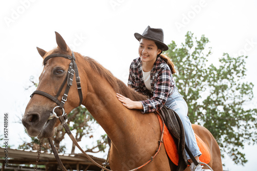 beautiful cowboy girl riding horse while stroking on outdoor background