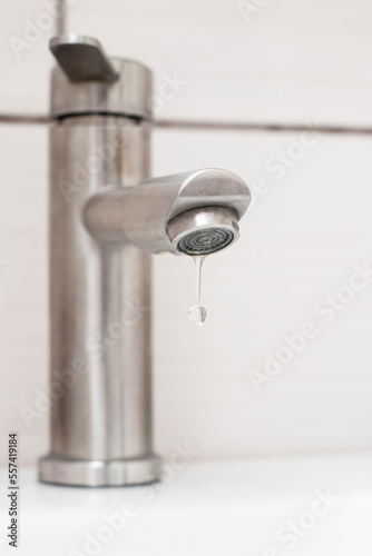 Water dripping from the faucet in the bathroom. Water faucet close-up. Saving water