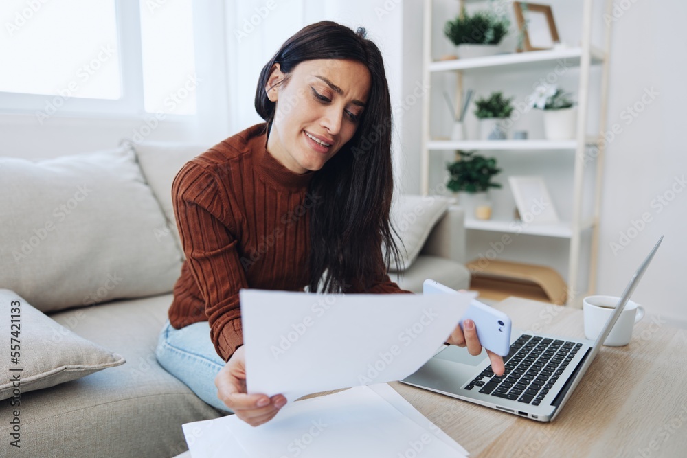 A woman does financial calculations and document analysis at home with a laptop, a freelancer works A woman does financial calculations and document analysis at home with a laptop, a freelancer works