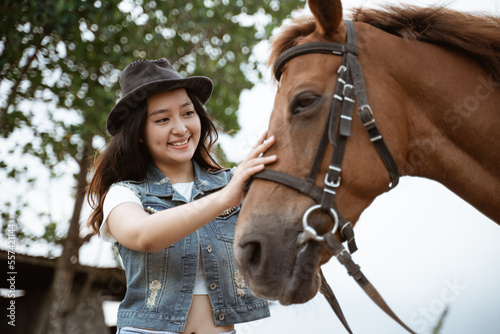 beautiful asian cowboy girl standing beside horse on outdoor background © Odua Images