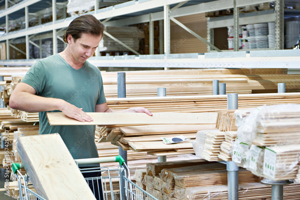 Man chooses and buys wooden boards in store