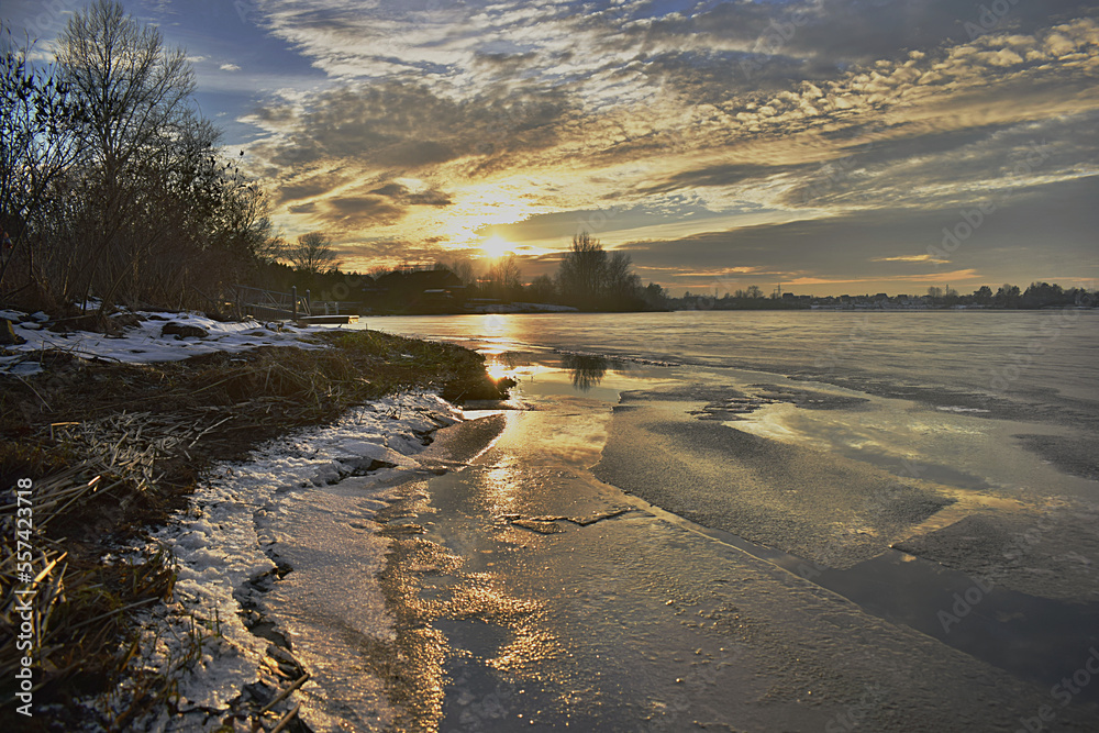 River with thin ice at the setting sun