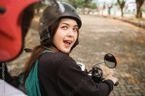 High school students wearing helmets and jackets looking back chatting while riding motorbikes together