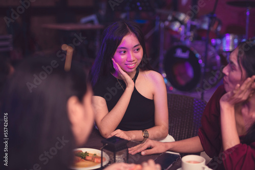 A good-looking Asian lady rests her face on her palm as she attentively listens to her friend gossiping about a recent issue. Friends catching up with each other while eating out in a restaurant.
