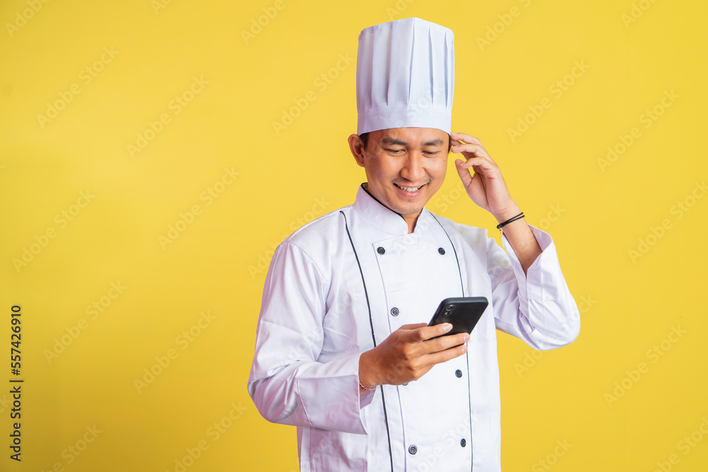 asian male chef wearing chef jacket using a smartphone on isolated background asian male chef wearing chef jacket using a smartphone on isolated background
