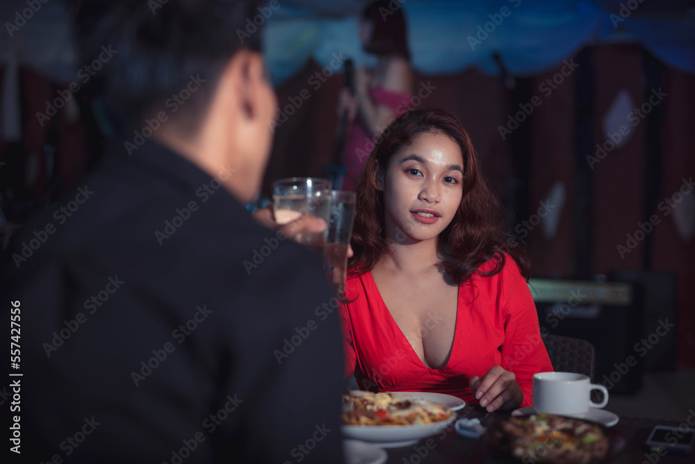 Asian couple makes toast to their romantic relationship as they celebrate valentine's day by having a dinner date at an indoor restaurant with live band. Asian couple makes toast to their romantic relationship as they celebrate valentine's day by having a dinner date at an indoor restaurant with live band.