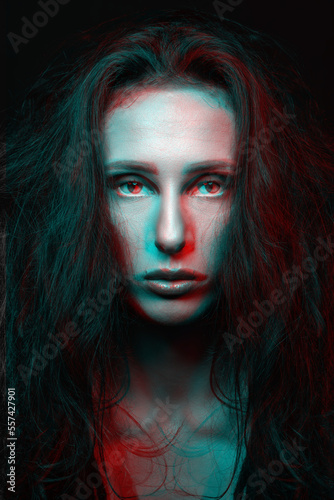 Sci-fi and fashion concept. Studio portrait of beautiful woman in red and blue color split effects. Model with long and dark dreadlocks looking at camera with seductive look. Futuristic looking style