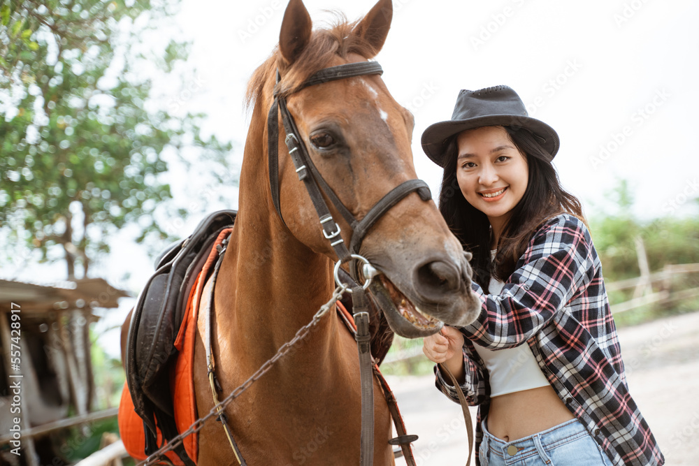 Fototapeta premium beautiful asian cowboy girl standing beside horse on outdoor background