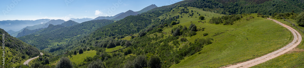 Panorámica de un paisaje verde en las montañas de Asturias, con carreteras curvas y montañas al fondo en verano de 2021