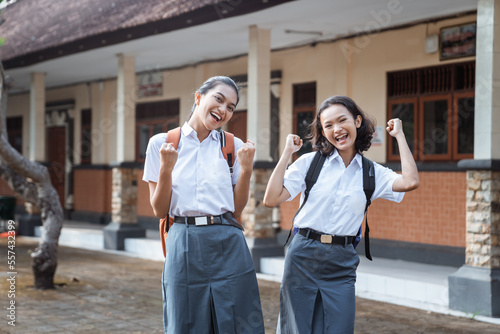 Two excited high school teens standing laughing in the schoolyard © Odua Images