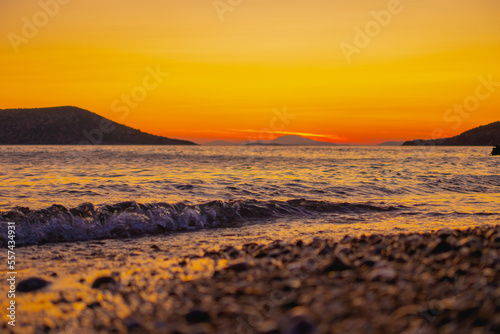 Sunset in meddeterian sea in greek islands and orange background with waves in sea © Kaspars