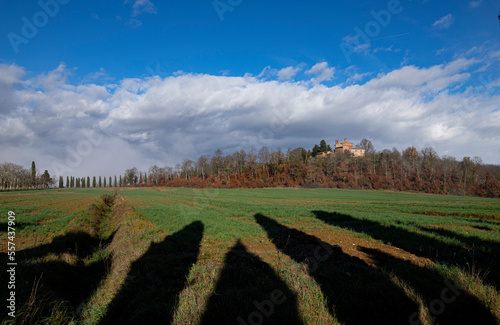 Tuscan countryside, on the hill Hermitage of San Galgano in Montesiepi, cloudy sky and shadows of cypresses on the meadow in the foreground. photo