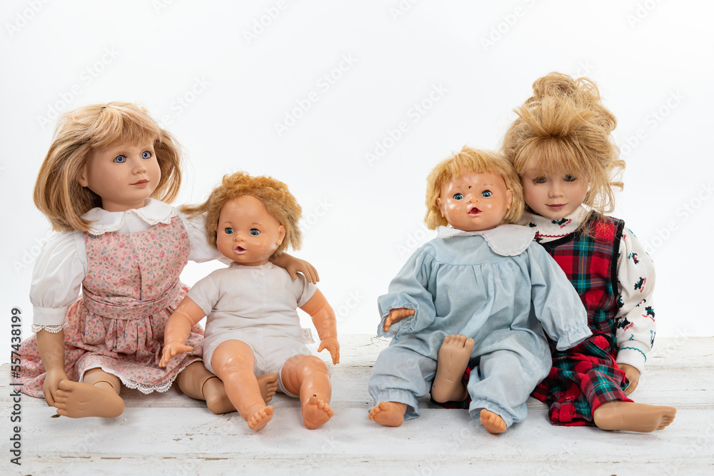 Collection of multiple dolls sitting on a rough white wooden table isolated on white with copy space Collection of multiple dolls sitting on a rough white wooden table isolated on white with copy space