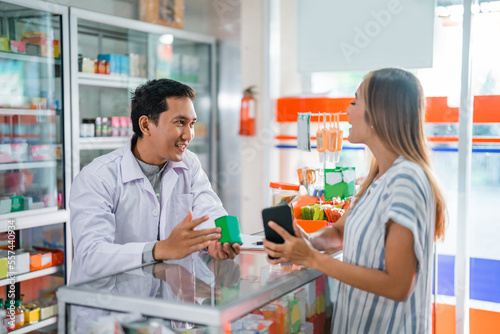 male pharmacist giving medicine to female customer at the pharmacy