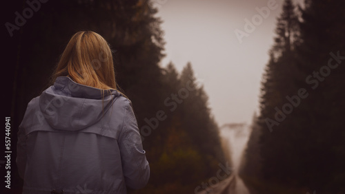 Woman walking along a dark forest passage