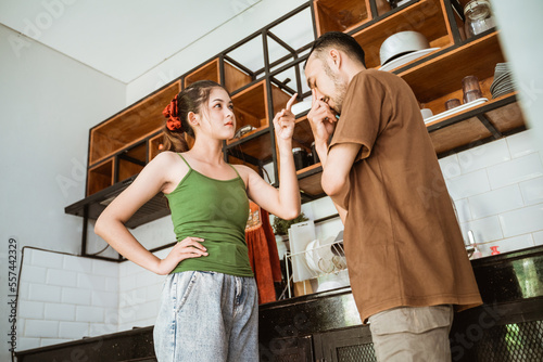 young woman getting angry at man while fighting in kitchen background