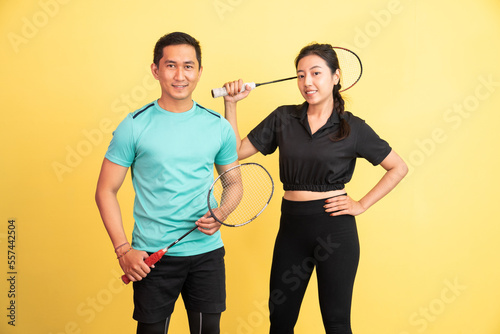 smiling asian woman and man standing holding racket on isolated background