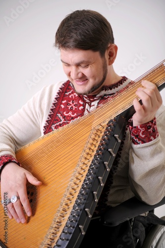 young handsome male Cossack of Ukraine plays the harp and smiles the musician holds the kobza and looks at 30 years old white and red embroidered shirt made of natural fabric Ukrainian symbol