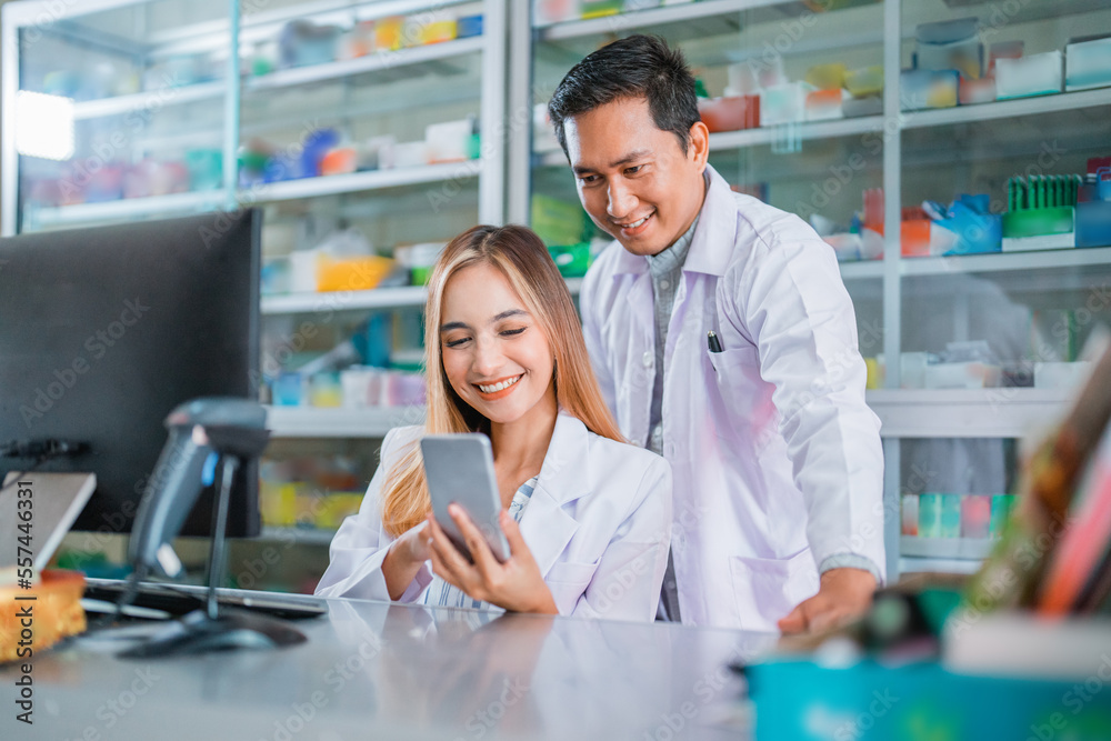 asian female and male pharmacist using smartphone together at drugstore asian female and male pharmacist using smartphone together at drugstore