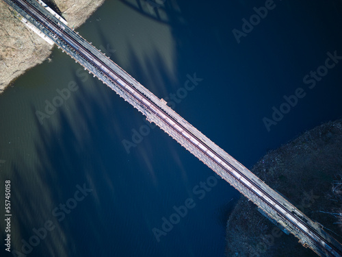 Aerial view of steel underspanned suspension railway bridge over Bobr River in Pilchowice, Wonderfull lake with islands and green forests in mountains on a early spring day in Pilchowice, Poland photo