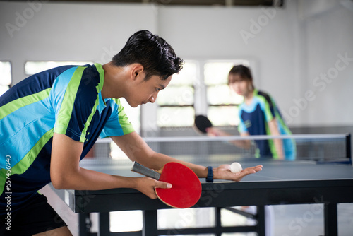 Male athlete carrying a ball and paddle while serving a ping pong game at a ping pong table