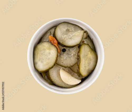 Pickled sliced cucumbers in brine in a bowl on yellow background. Traditional meat snacks. Healthy fermented food.