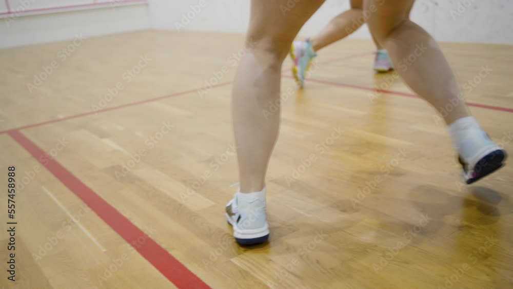 Female athletes play squash moving actively on court