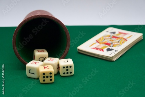 Poker dice game on green carpet and cards