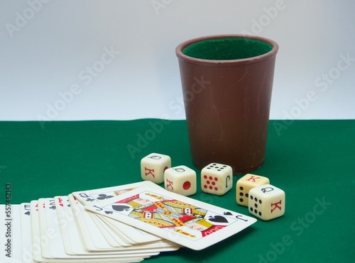 Poker dice game on green carpet and cards