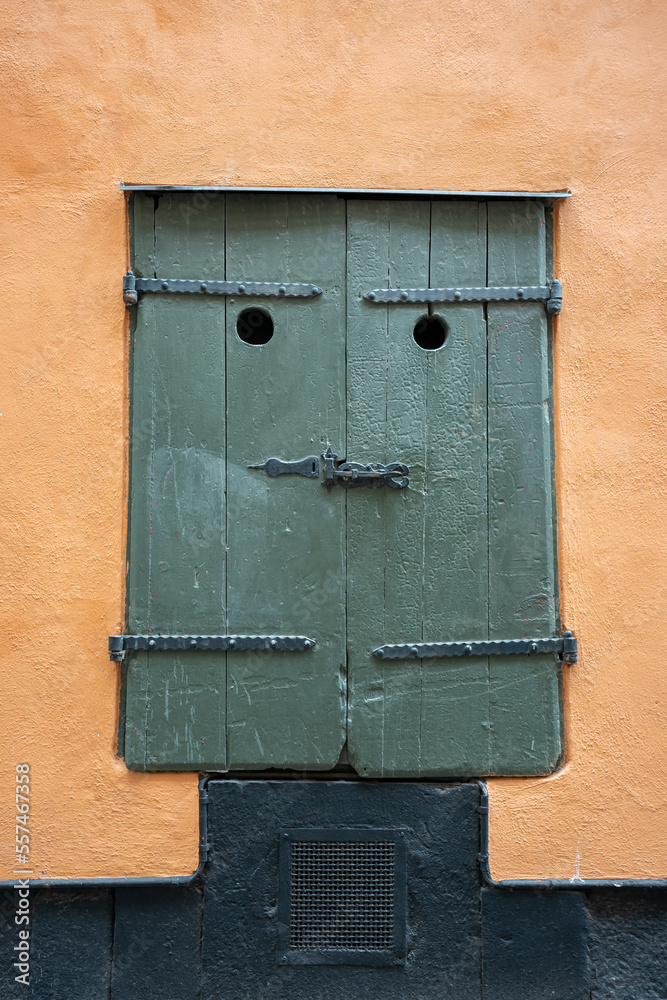 Close up of funny face like green wooden window shutter on building exterior.
