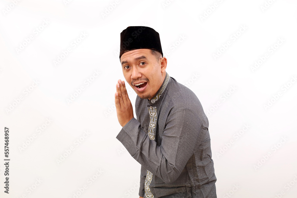 Asian muslim man standing with telling a secret gesture. Isolated on white background Asian muslim man standing with telling a secret gesture. Isolated on white background