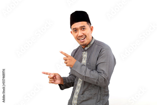 Happy asian muslim man standing while pointing sideways. Isolated on white background