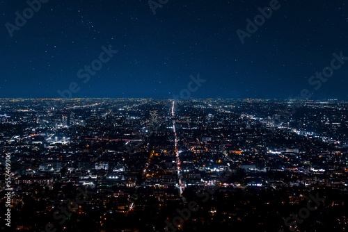 Fototapeta Naklejka Na Ścianę i Meble -  Drone shot of illuminated buildings and skyscrapers with beautiful stars shining in dark sky at modern Los Angeles city during night